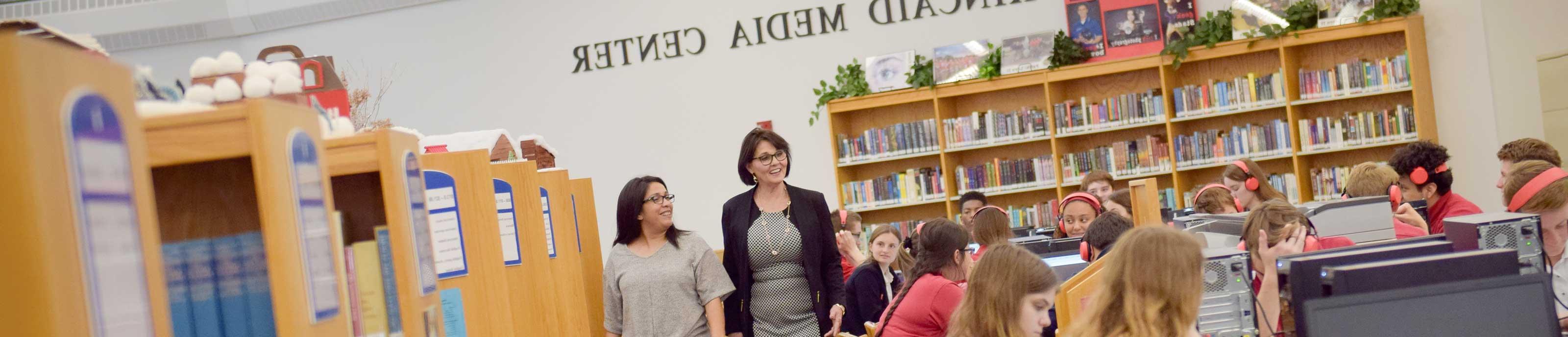 A school principal walks by during a high school class in a media center